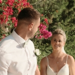 Ross and Suzi walking hand in hand along a vibrant, flower-lined path at Liopetro after their wedding ceremony, with smiles of joy and love.