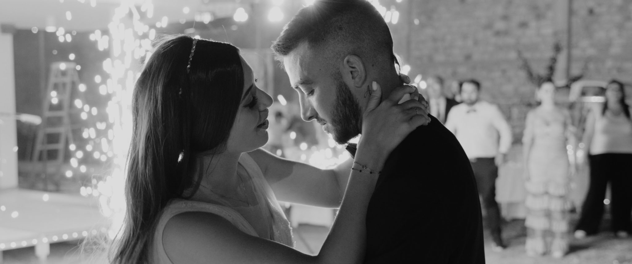 Bride and groom in emotional first dance with indoor fireworks and guests in background