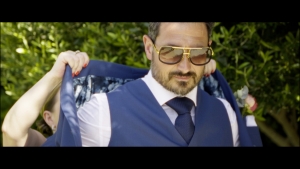 Groom Stephen looking stylish in a blue suit and aviator sunglasses